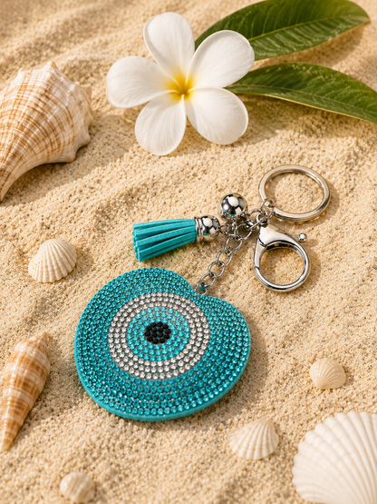 Turquoise keychain with decorative elements on sand with shells and a flower