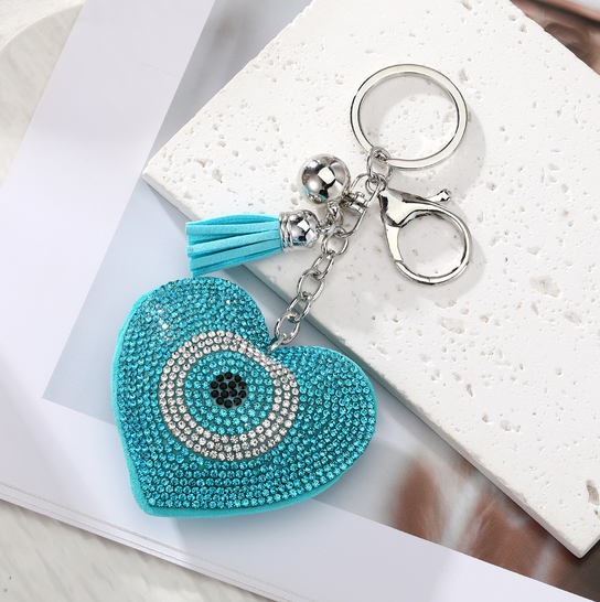 Turquoise heart-shaped keychain with decorative elements on a marble surface