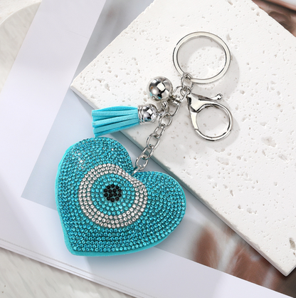 Turquoise heart-shaped keychain with decorative elements on a marble surface