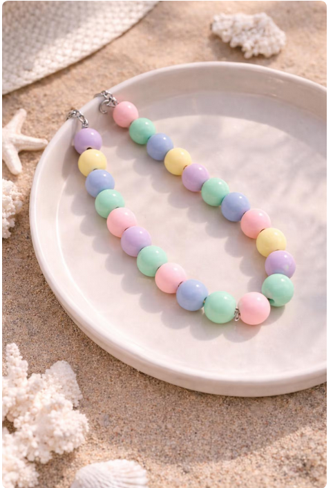 Pastel beaded necklace on a white plate with coral decorations