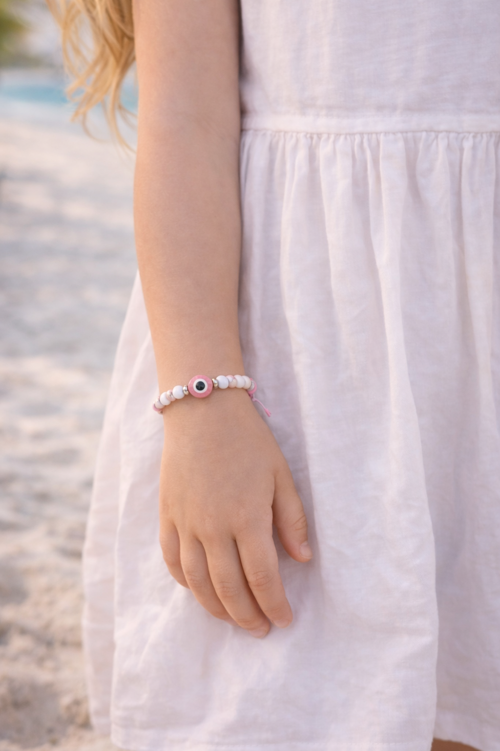 Person wearing a bracelet with a beach in the background