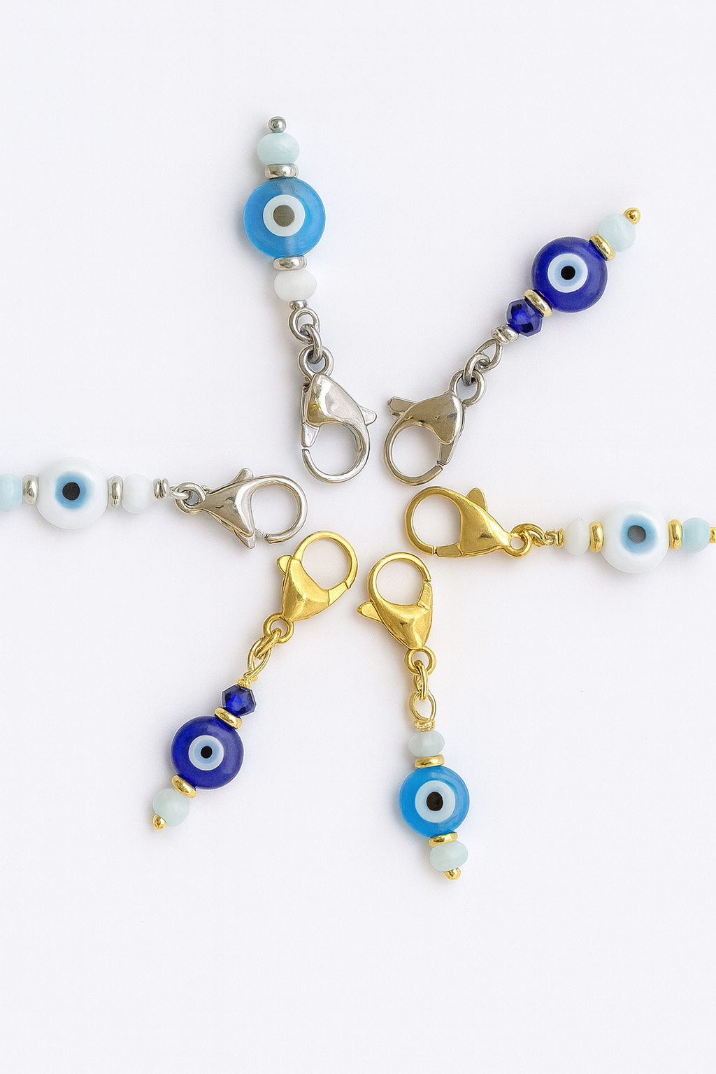Evil eye charms on keychains with gold and silver clasps on a white background