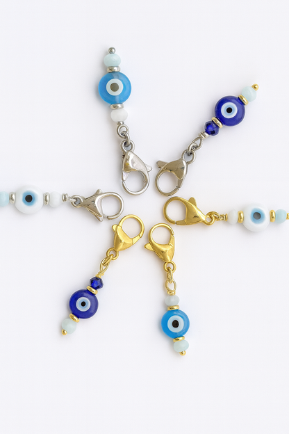 Evil eye charms on keychains with gold and silver clasps on a white background