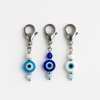 Three evil eye keychain charms with blue and white beads on a white background