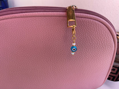 Pink pouch with a gold zipper and blue evil eye charm