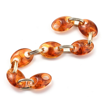 Orange chain bracelet with gold accents on a white background