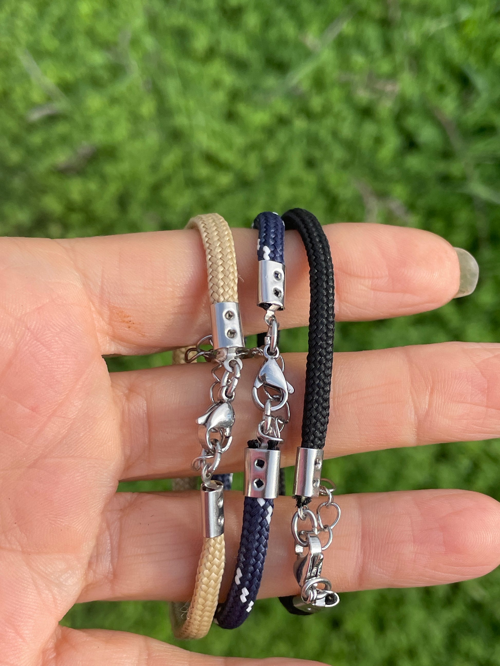 Multiple bracelets on a hand with a green blurred background