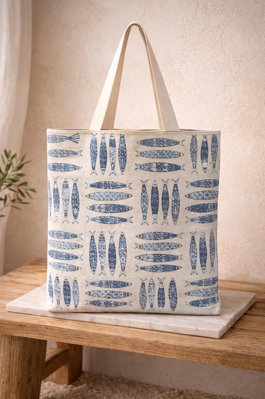 Tote bag with blue fish pattern on a wooden surface.