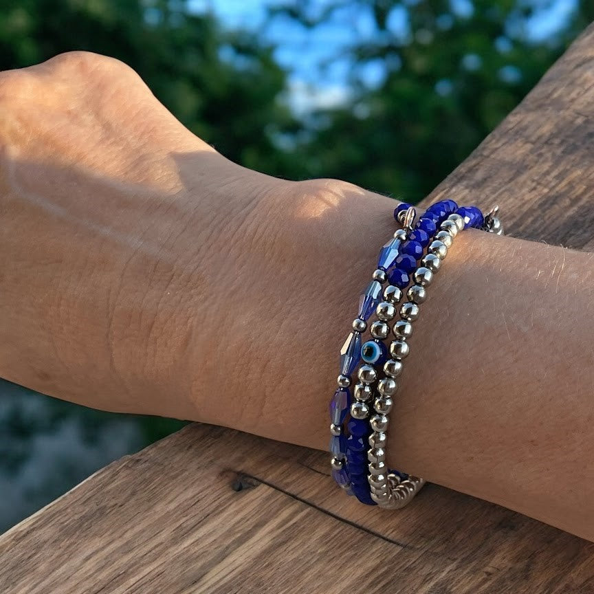 Person wearing a blue beaded bracelet on a wooden surface with a blurred natural background