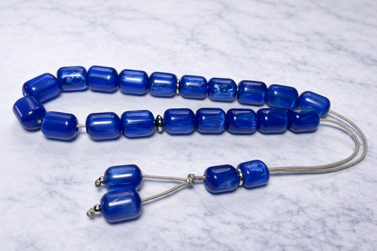 Blue beaded worry bead on a light gray marble background
