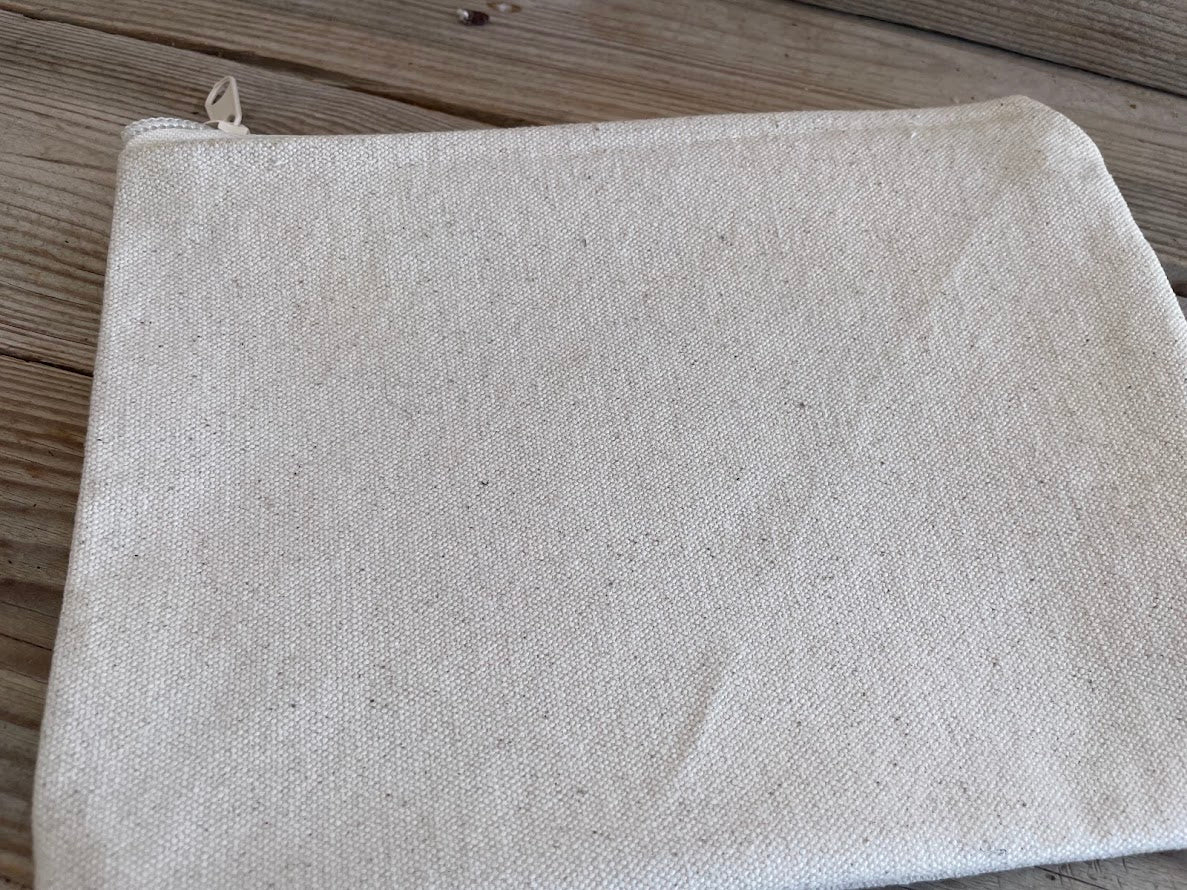 Beige fabric pouch with a zipper on a wooden surface