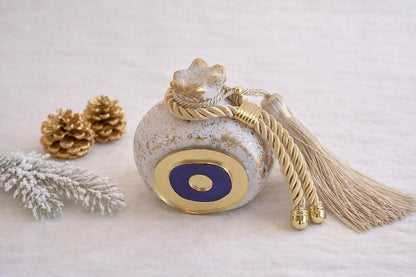 Decorative bottle with tassel and gold accents on a light background