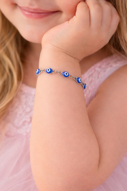 Child's arm wearing a blue beaded bracelet with a pink background