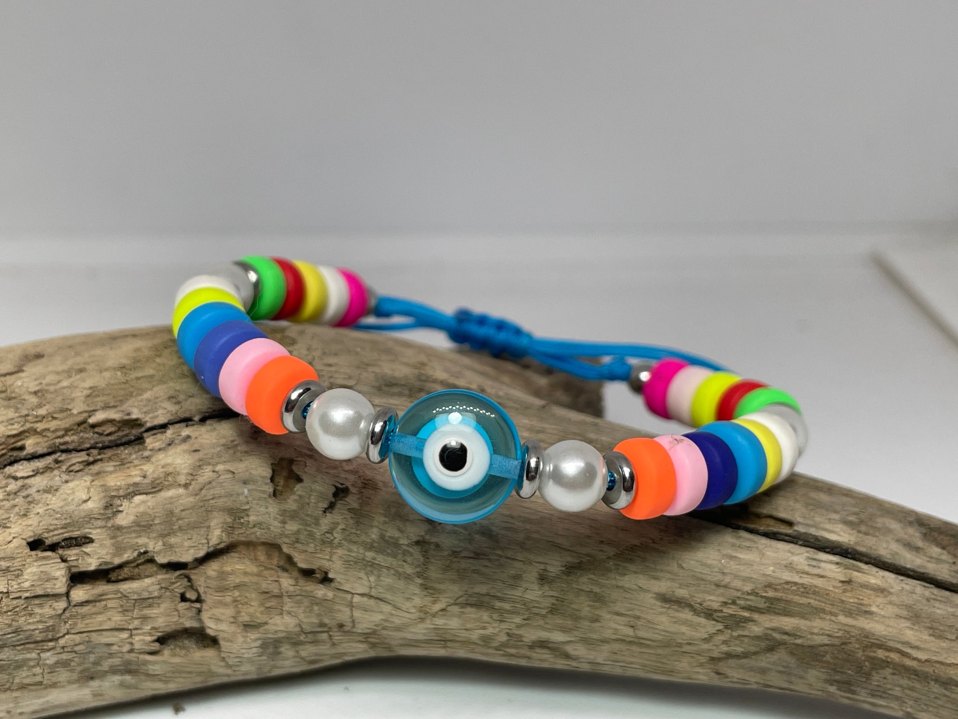 Colorful beaded bracelet with a blue evil eye charm on a wooden surface