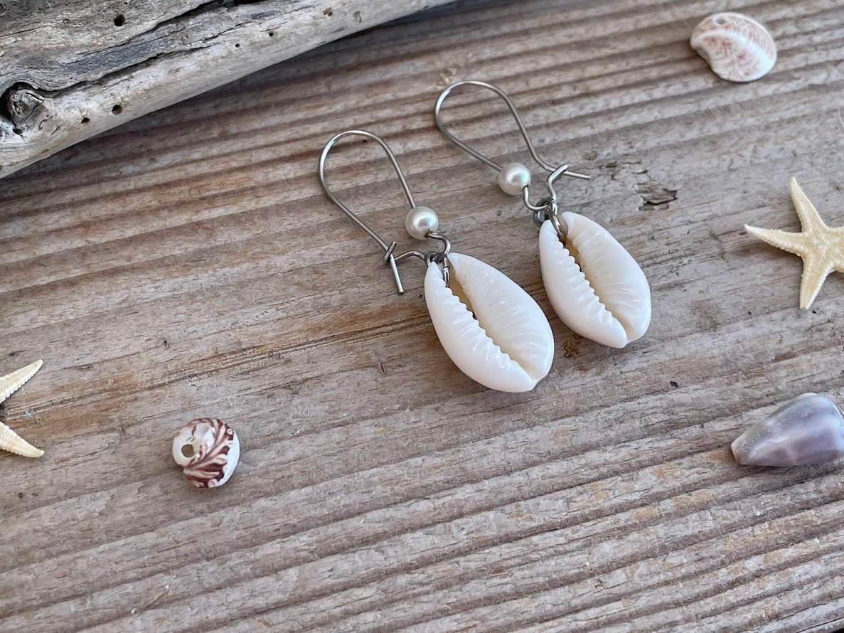 Shell earrings on a wooden surface with shells and starfish around