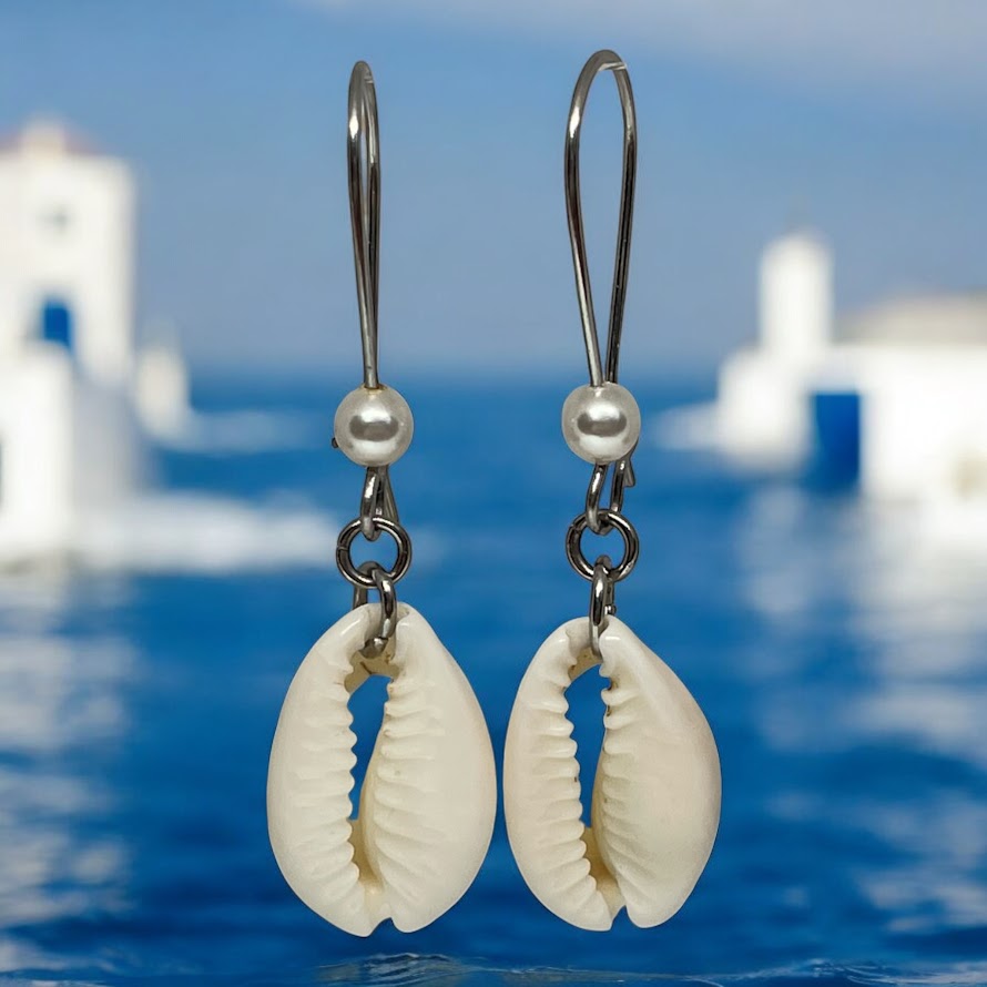 Shell and pearl earrings with a blurred coastal background