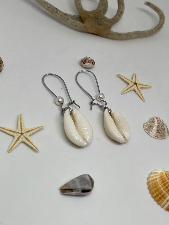 Pair of shell earrings with starfish and shells on a white background