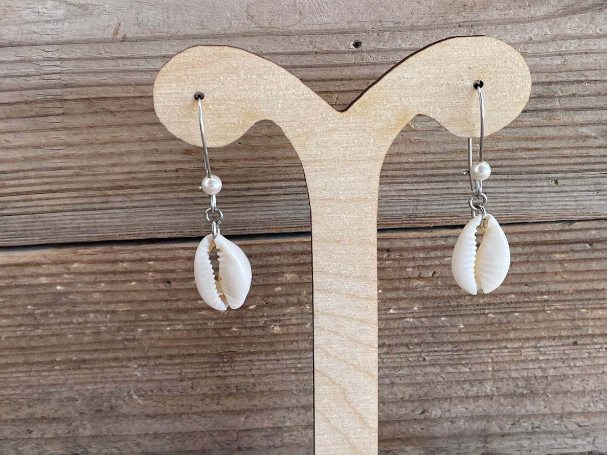 Shell earrings on a wooden display stand against a wooden background