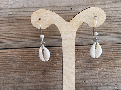 Shell earrings on a wooden display stand against a wooden background