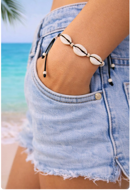 Person wearing a shell bracelet on a beach with palm trees in the background