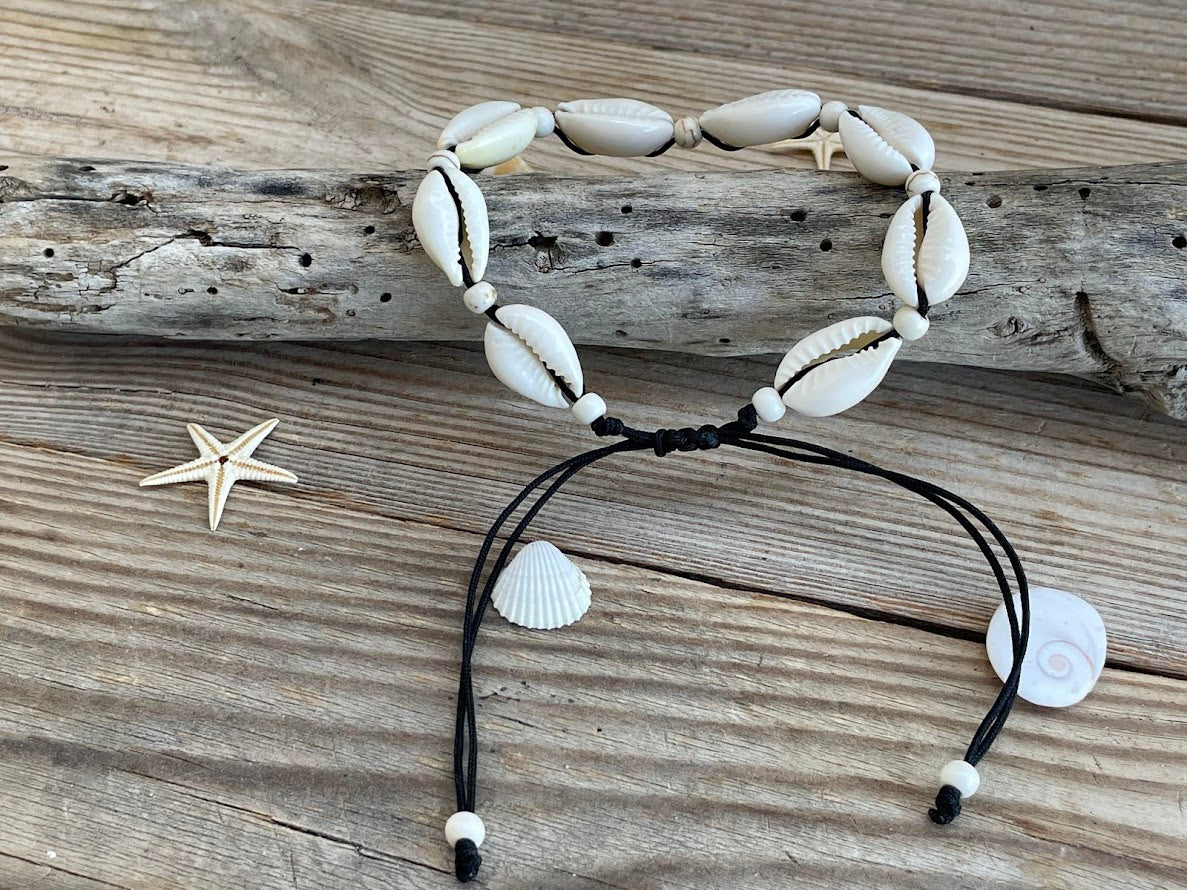 Shell bracelet with black cord on a wooden surface