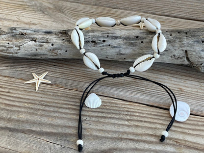 Shell bracelet with black cord on a wooden surface