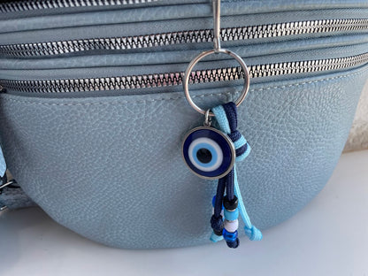 Blue evil eye keychain hanging from a gray bag