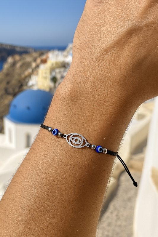 Bracelet with a symbol worn on a wrist, with a scenic background of a blue-domed church.