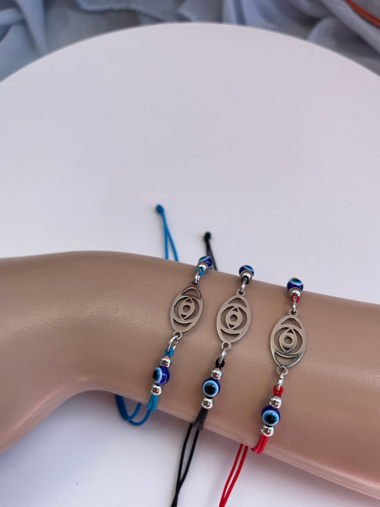 Three bracelets with decorative elements on a mannequin wrist against a neutral background