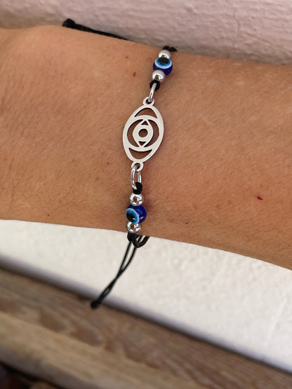 Bracelet with eye symbol on wrist against a neutral background