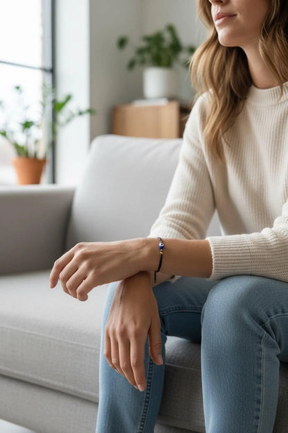 Woman sitting on a couch wearing a white sweater and blue jeans, with a blurred background.