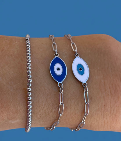 Two silver bracelets with blue and white eye designs on a wrist against a blue background