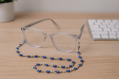 Clear glasses with a blue beaded chain on a wooden surface with a keyboard in the background