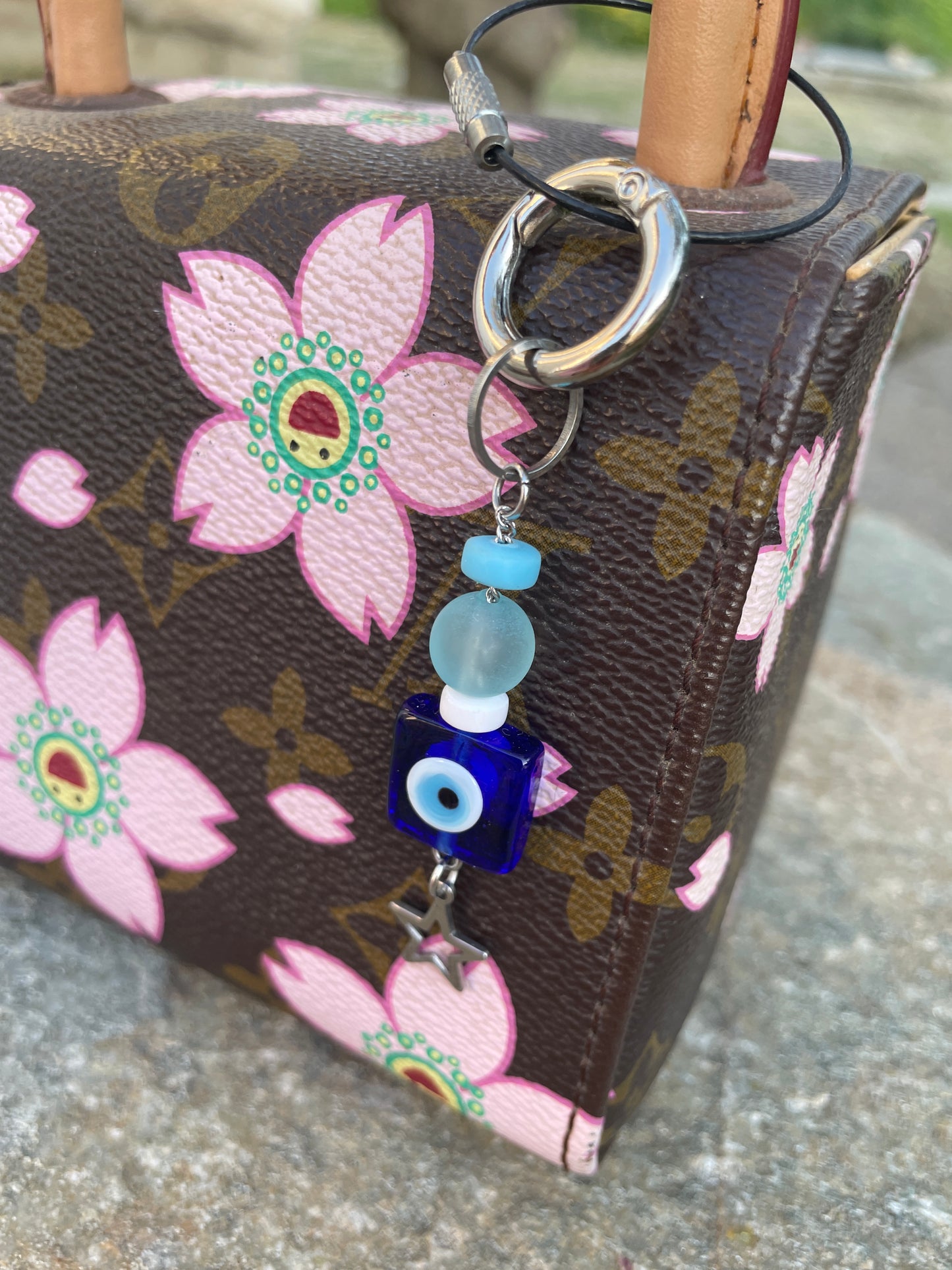 Floral-patterned pouch with decorative keychain on a textured surface
