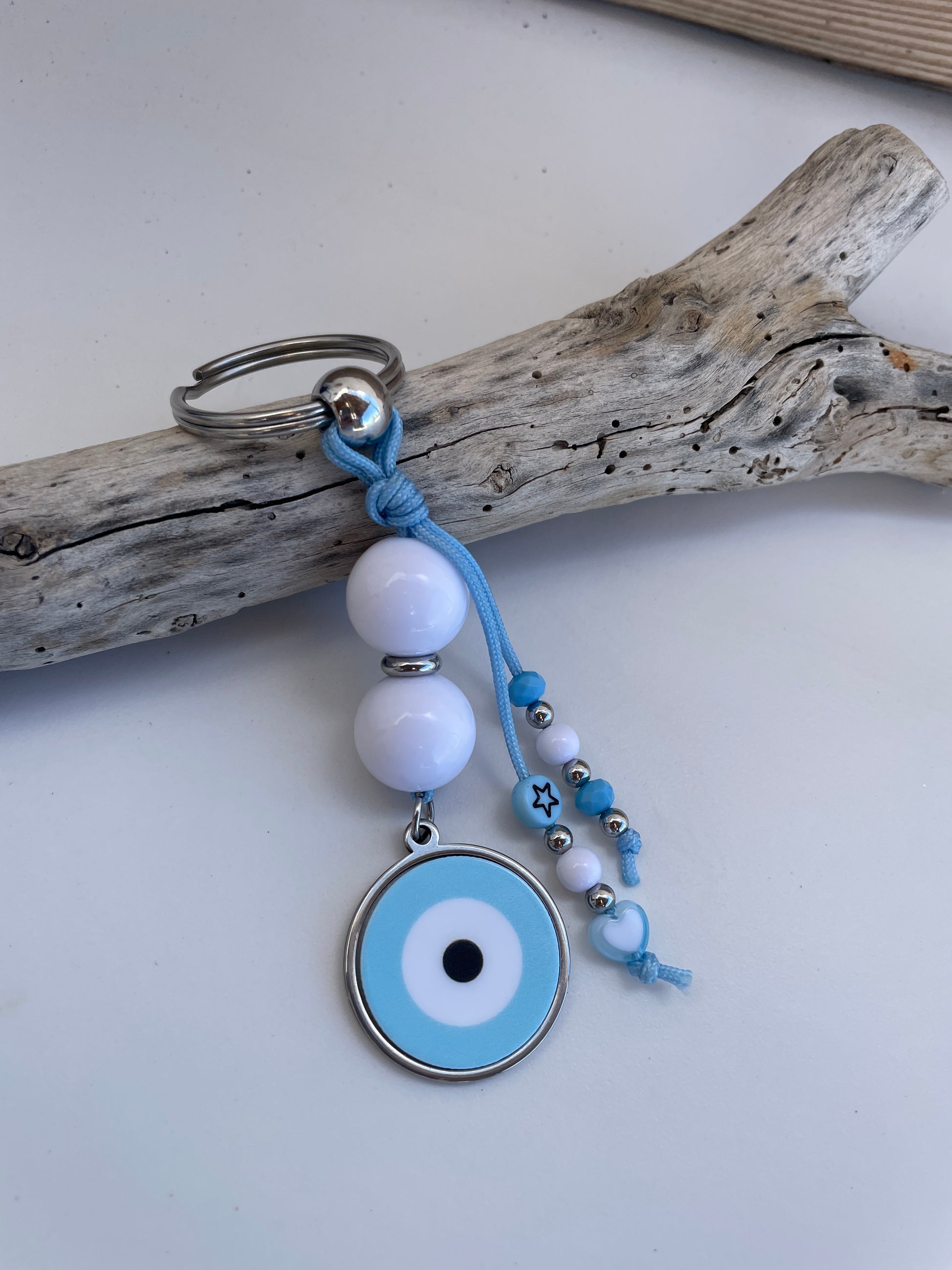 Keychain with blue string, white beads, and a circular charm on a white background