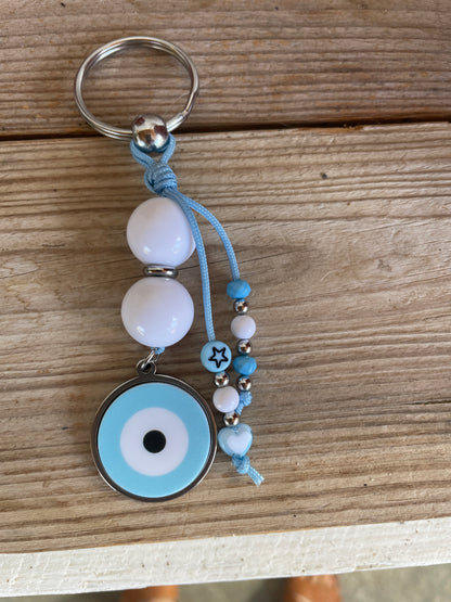 Keychain with blue and white beads and an eye-shaped charm on a wooden surface