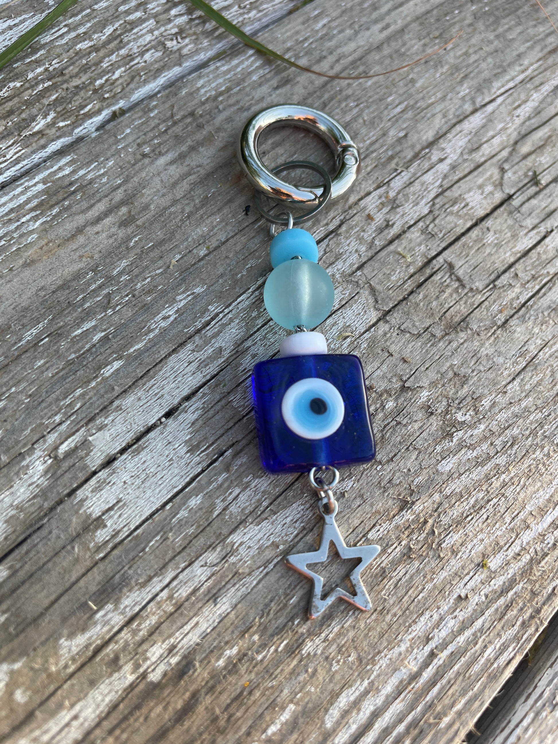 Keychain with blue square bead, white star charm, and blue bead on wooden surface