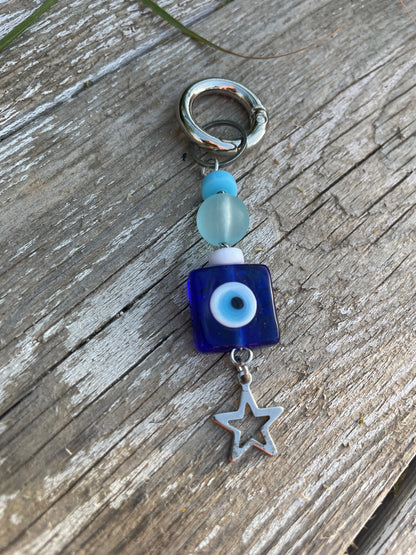 Keychain with blue square bead, white star charm, and blue bead on wooden surface