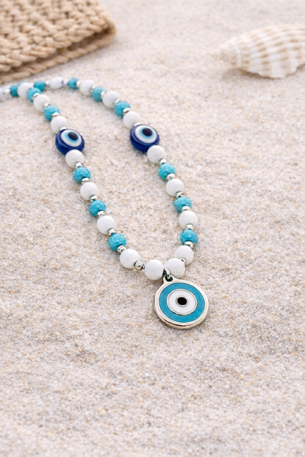 Necklace with blue and white evil eye charms on a sandy background