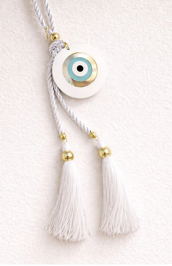 Evil eye charm with tassels on a white background