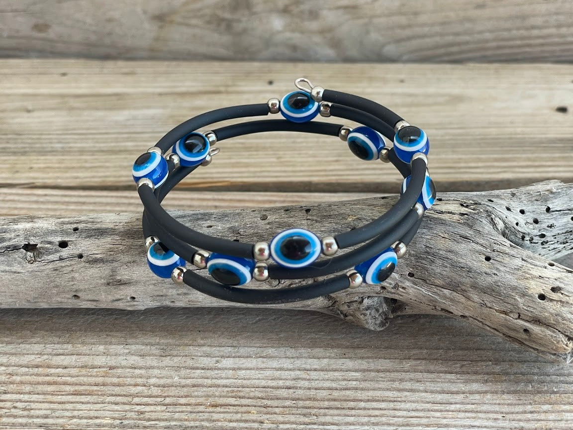 Black rubber bracelet with blue and silver beads on a wooden surface