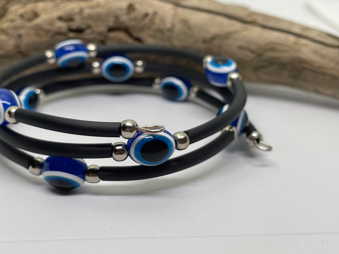 Black rubber bracelet with blue and silver beads on a white surface.