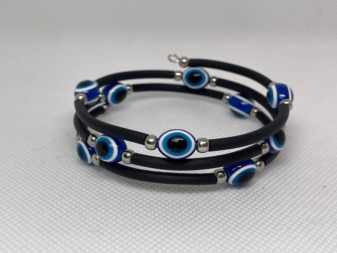 Stack of black bracelets with blue and silver eye designs on a light gray background