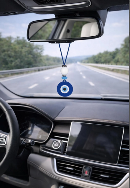 Car interior with a blue evil eye charm hanging from the rearview mirror.