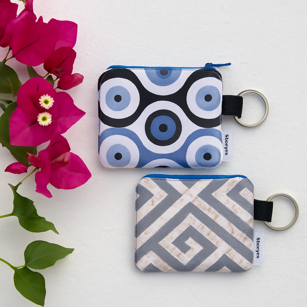 Two small pouches with geometric patterns and keychains on a white background with pink flowers.