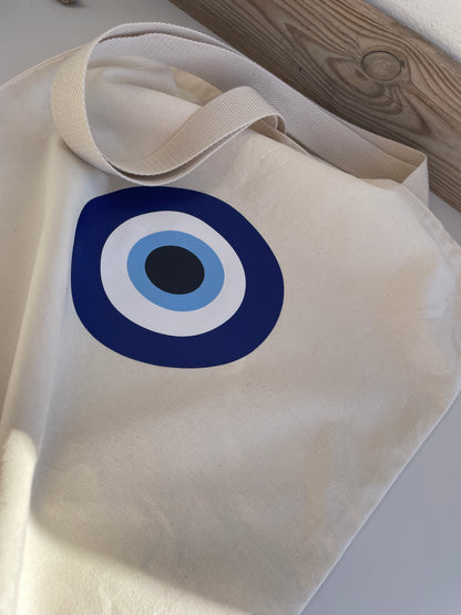 Beige tote bag with a blue and white circular design on a wooden surface.