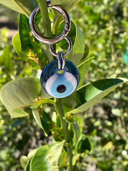 Blue evil eye keychain on green leaves