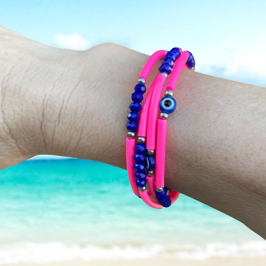 Pink and blue beaded bracelet on a wrist with a beach background