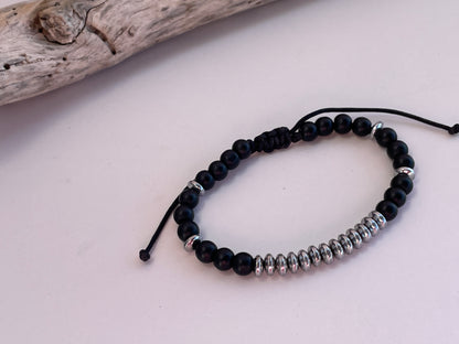 Black beaded bracelet with silver accents on a light pink background