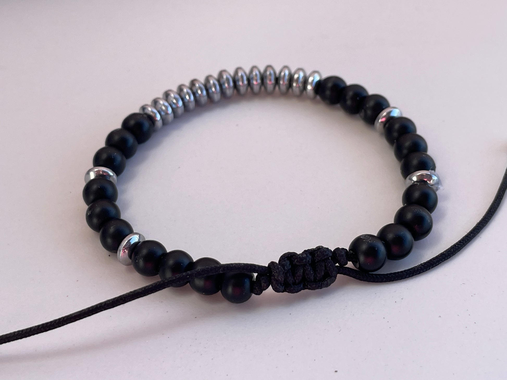 Black beaded bracelet with silver accents on a light background